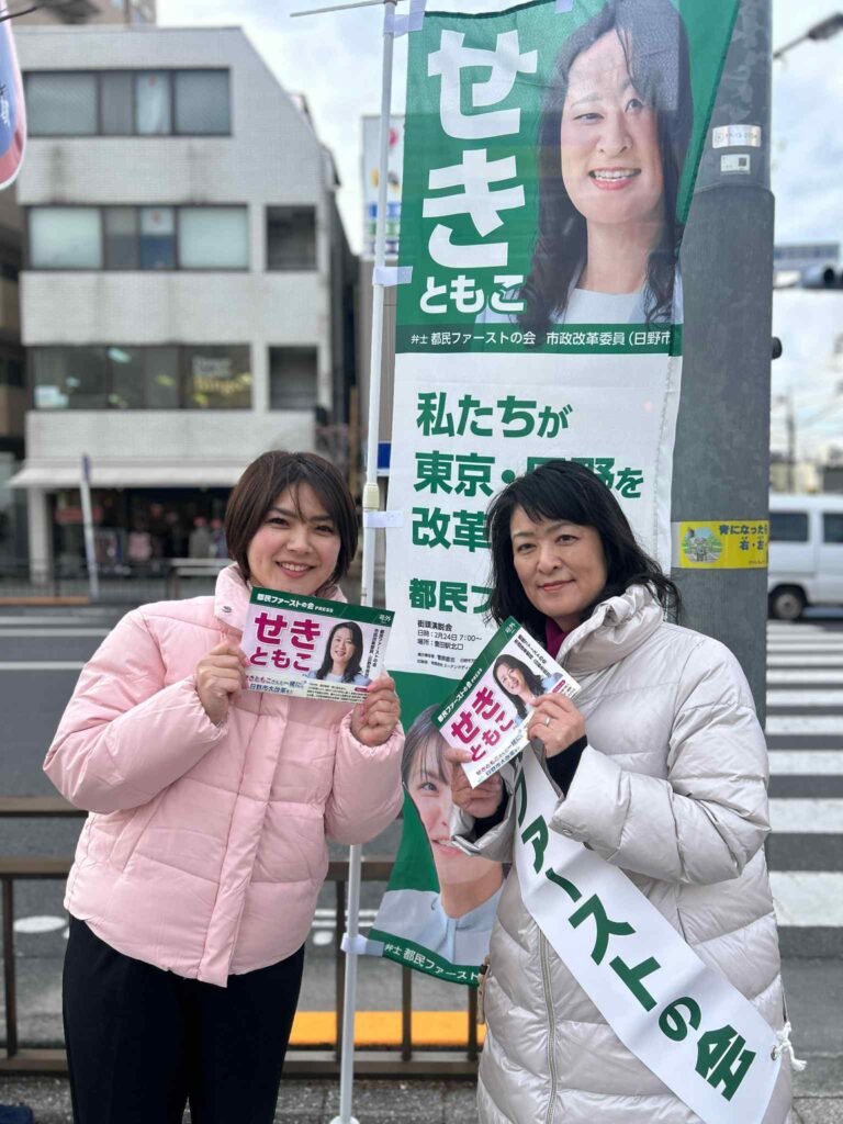 旗の前にいる寺前ももこ議員とせきともこ